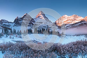 First snow. Mount Assiniboine, also known as Assiniboine Mountain, is a pyramidal peak mountain located on the Great Divide.