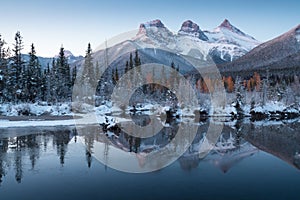 First snow Almost near perfect reflection of the Three Sisters Peaks in the Bow River. Canmore in Banff National Park Canada photo