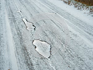 First snow. Pothole pits on a snowy white road