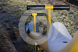 The first snow in winter on the playground outside. Seasonality concept. Snow lies on the swing.