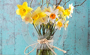 First spring narcissus in the wase with some branches. On the green wooden background