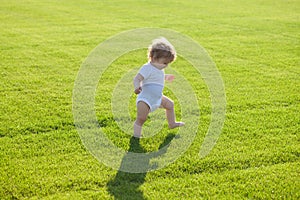 First step. Baby bare legs standing on green grass. Healthy child.