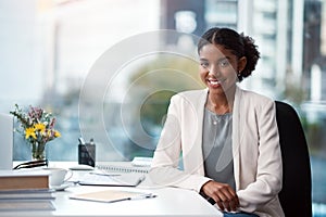 The first step to succeeding is showing up. Portrait of a confident young businesswoman working at her desk in a modern