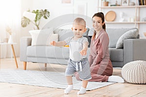 First Steps. Adorable smiling baby boy learning how to walk at home,