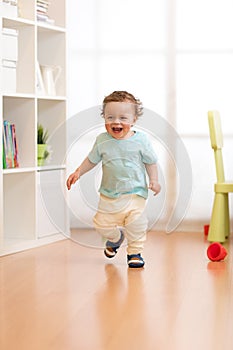 First steps of baby boy toddler learning to walk in living room. Footwear for little children.