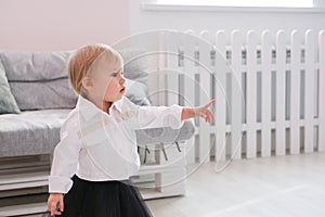 First steps of baby girl learning to walk in white sunny bedroom