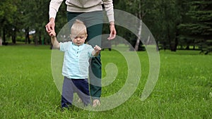 First steps of boy`s child. First with the help of mother, then independent steps