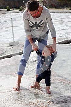 First steps of the little boy, mother and son on travertine terrace pool in Pamukkale, Turkey