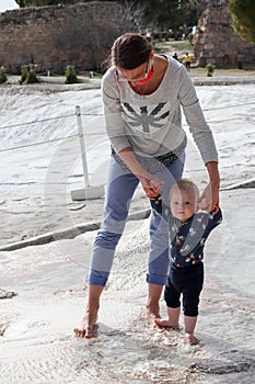 First steps of the little boy, mother and son on travertine terrace pool in Pamukkale, Turkey