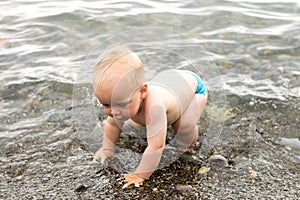 First steps in the sea. Funny kid boy trying to walk in the water