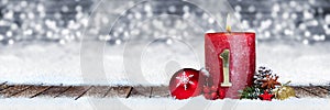First sunday of advent red candle with golden metal number one on wooden planks in snow front of panorama bokeh background
