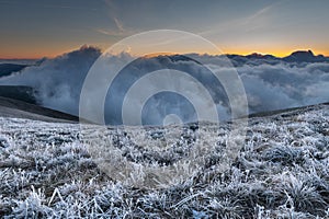 First sunlight on a early cold winter morning with frozen grass landscape and bright foggy glow. Misty winter morning