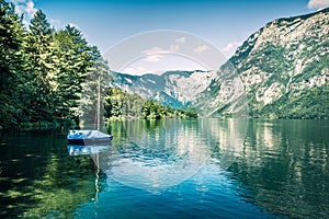 First sunlight glowing surface of Bohinj lake. Beautiful summer scene of Triglav national park. Great morning view of Julian Alps