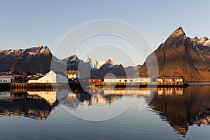 First sunlight on the historic buildings at Hamnøy with snowclad mountains in the background, Lofoten, Norway