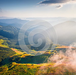 First sunlights glowing foggy mountain hills and valleys.