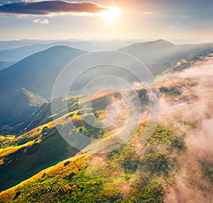 First sunlights glowing foggy mountain hills and valleys.