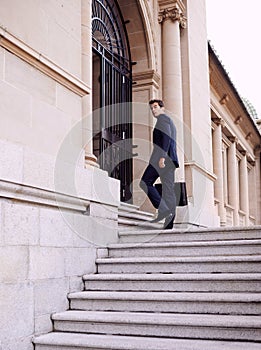 Always the first to arrive at the office...A handsome businessman with a briefcase standing outside a city building.