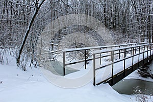 Untouched snow covered bridge over frozen creek