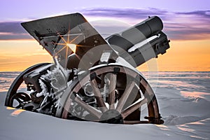 A first-world-war cannon surrounded by snow at sunrise