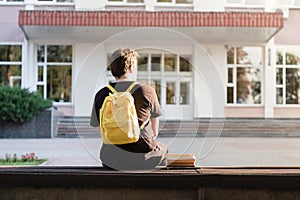 First year student sitting outside a university or school facility. Freshman waiting for the beginning of the classes photo