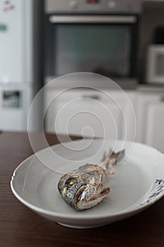 Fish bone left overs with a sliced lemon on a white oval plate.