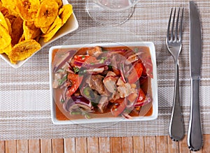 Fish ceviche and bowl of fried plantains chips are served in beautiful ceramic dishes