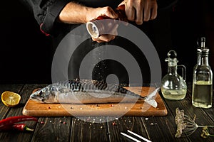 Fish chef prepares fresh mackerel in the kitchen. Scomber must be added with aromatic pepper before baking. European cuisine
