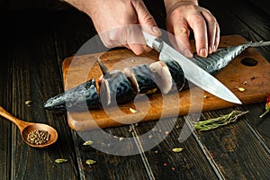 A fish chef prepares fresh mackerel in the kitchen. Scomber must be cut into small pieces before baking. Advertising space