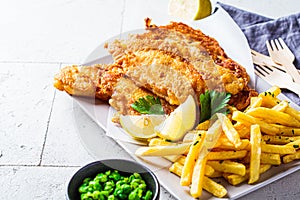 Fish and chips with green peas on gray tile background. British cuisine concept