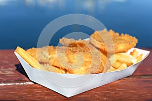 Fish and Chips served in a tray on a waterfront restaurant table