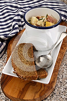 Fish chowder in a mug with bread on a plate