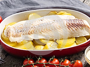 Fish cod baked in the oven with potatoes, diet healthy food. Dark old wooden rustic gray background, side view