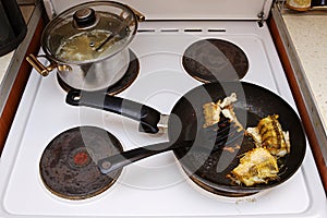 Fish cooked in a frying pan on an electric stove. The lid is open. Unhealthy fatty foods. photo