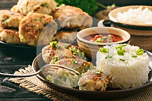 Fish cutlets with broccoli served with boiled rice.
