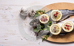 Fish dish cooking with various ingredients. Raw rainbow trout with lemon.