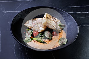 Fish dish: fried cod with spinach and capers in saffron sauce