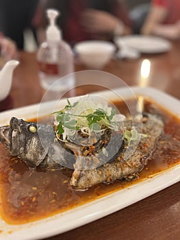 Fish dishes with broth served on a concave square plate