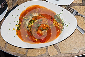 Fish dumpling with corn, tomatoes and parsley on white plate