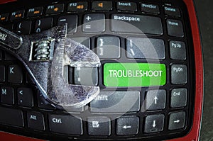 Fish eye effect. Troubleshoot green button on dirty computer keyboard with wrench tool. photo