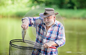 Fish farming pisciculture raising fish commercially. Fisherman alone stand in river water. Man senior bearded fisherman photo