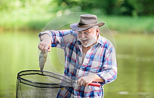 Fish farming pisciculture raising fish commercially. Fisherman alone stand in river water. Man senior bearded fisherman