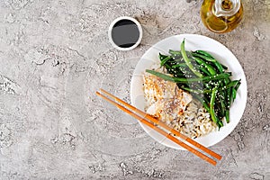 Fish fillet served with rice, soy sauce and green beans in white plate.
