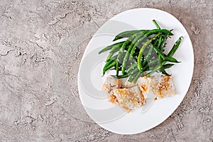 Fish fillet served with soy sauce and green beans in white plate.