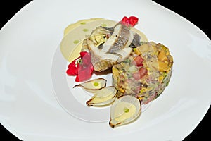 Fish fillet with vegetable salad and sauce on a white plate. Fish dish in a restaurant