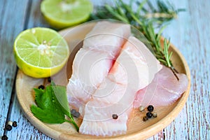 Fish fillet on wooden plate with ingredients celery for cookin, fresh raw pangasius fish fillet with lemon lime, meat dolly fish