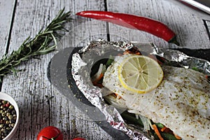 Fish in foil on a stone baked with lemon and vegetables