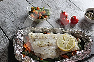 Fish in foil on a stone baked with lemon and vegetables