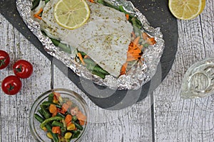 Fish in foil on a stone baked with lemon and vegetables