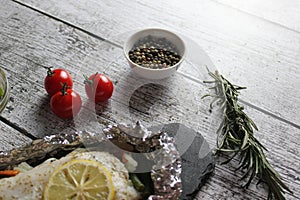 Fish in foil on a stone baked with lemon and vegetables