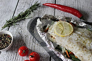 Fish in foil on a stone baked with lemon and vegetables